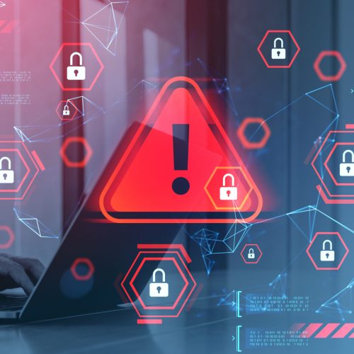 Person using laptop with red alert triangle and padlocks, futuristic graphic style, on a digital blue background. Concept of cybersecurity breach warning