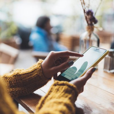 girl hold in hands yellow empty screen mobile phone close up, person type message on smartphone in sun cafe, relax tourist travels planning trip, hipster enjoy journey in cityscape, lifestyle holiday concept, internet online